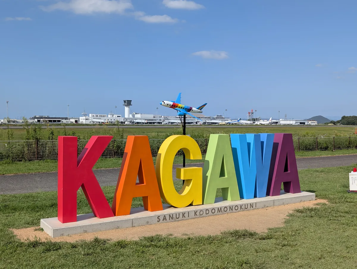 KAGAWAの文字モニュメントと上空を飛ぶ飛行機
