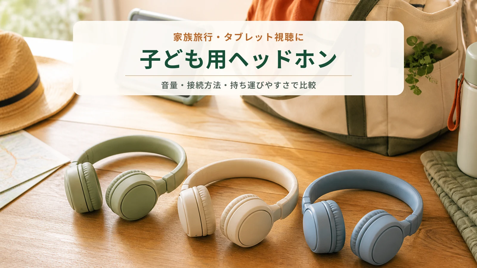 旅行バッグとタブレットの前に並べた3色の子ども用ヘッドホン