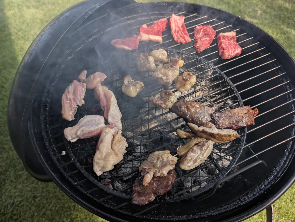 カルビやホルモンなどをBBQコンロで焼いている様子