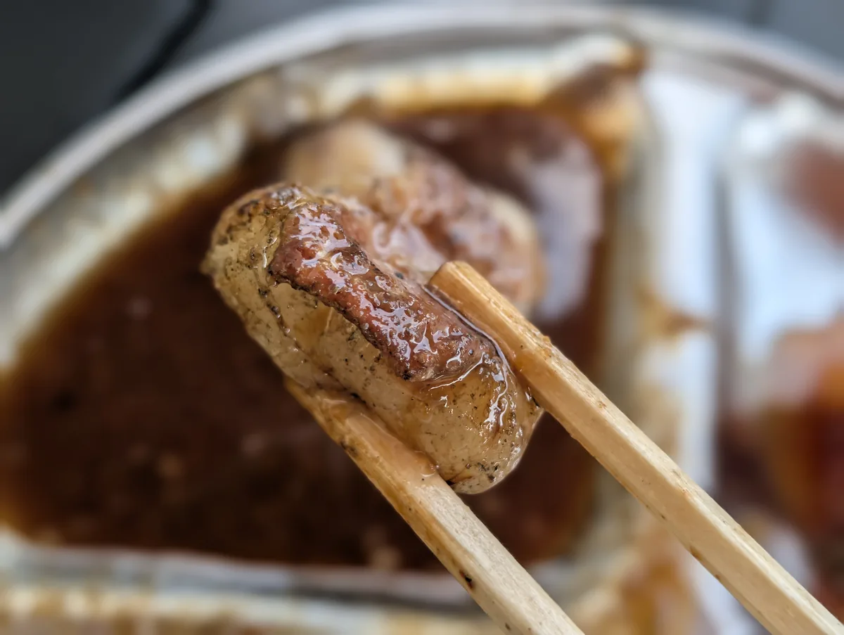 タレをつけた焼き上がりのお肉を箸で持ち上げたアップ